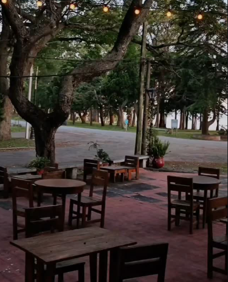 Patio exterior de la hostería con mesas de madera y luces colgantes